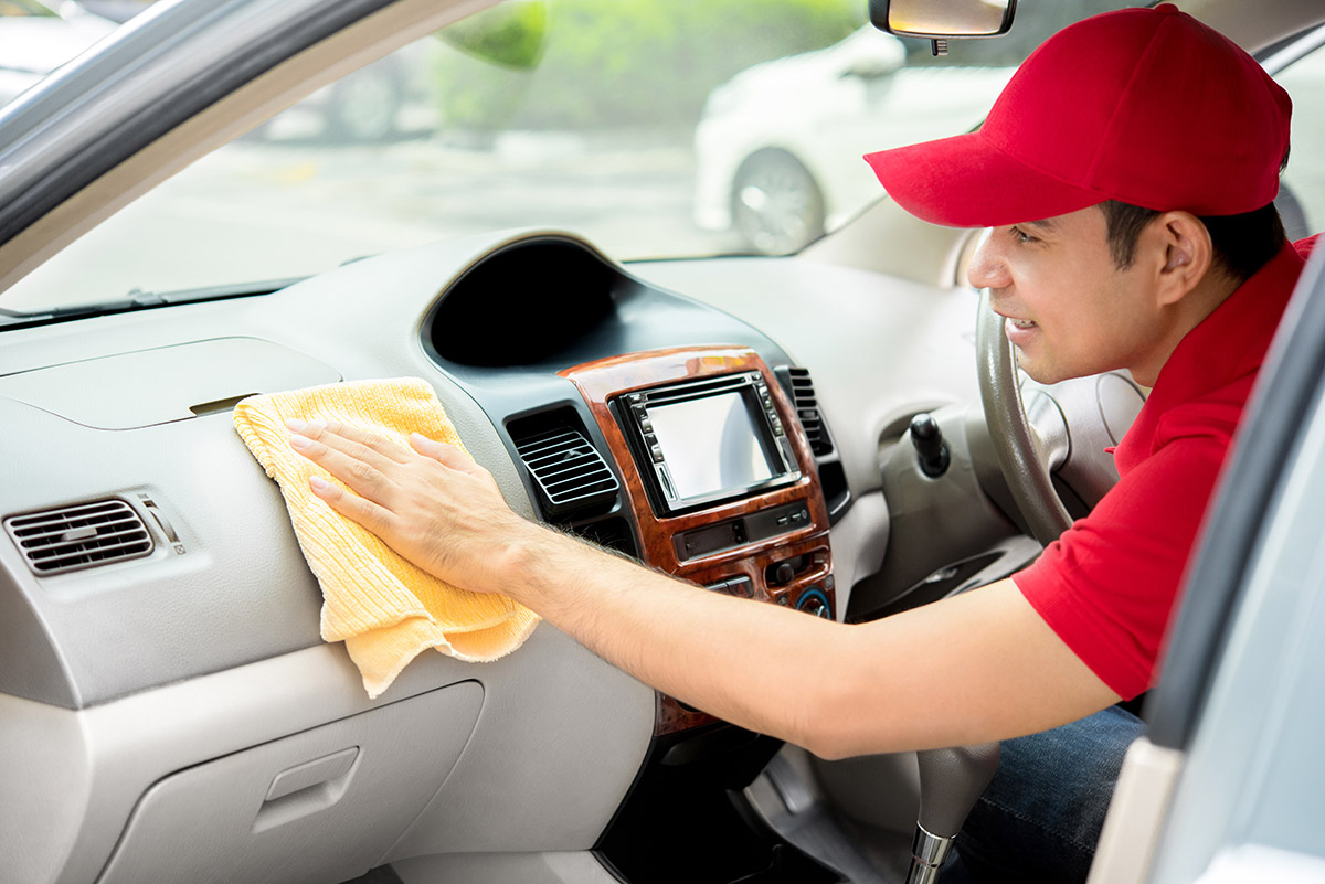 Detailer wipes down car dashboard