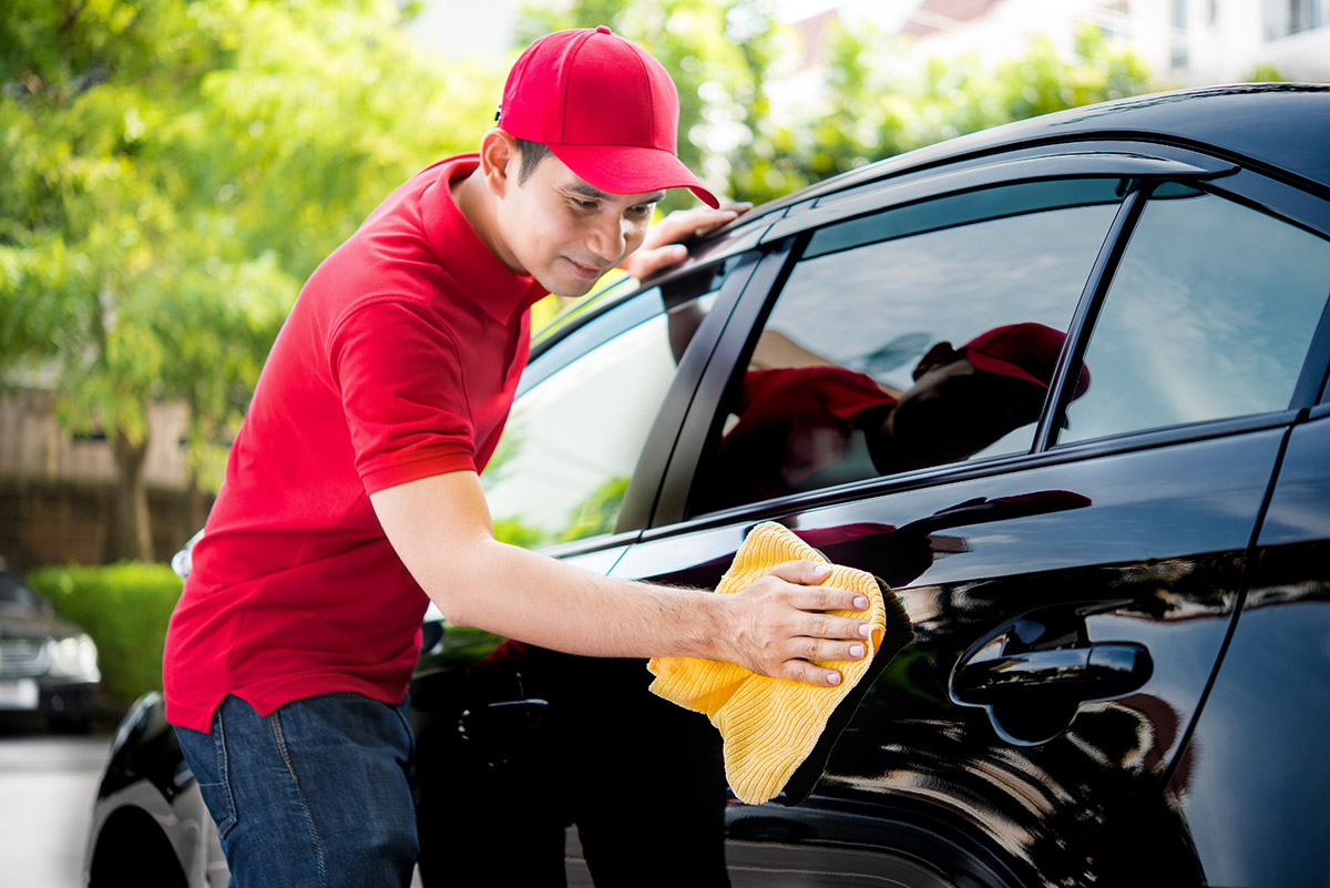 Detailer waxes and polishes black sedan